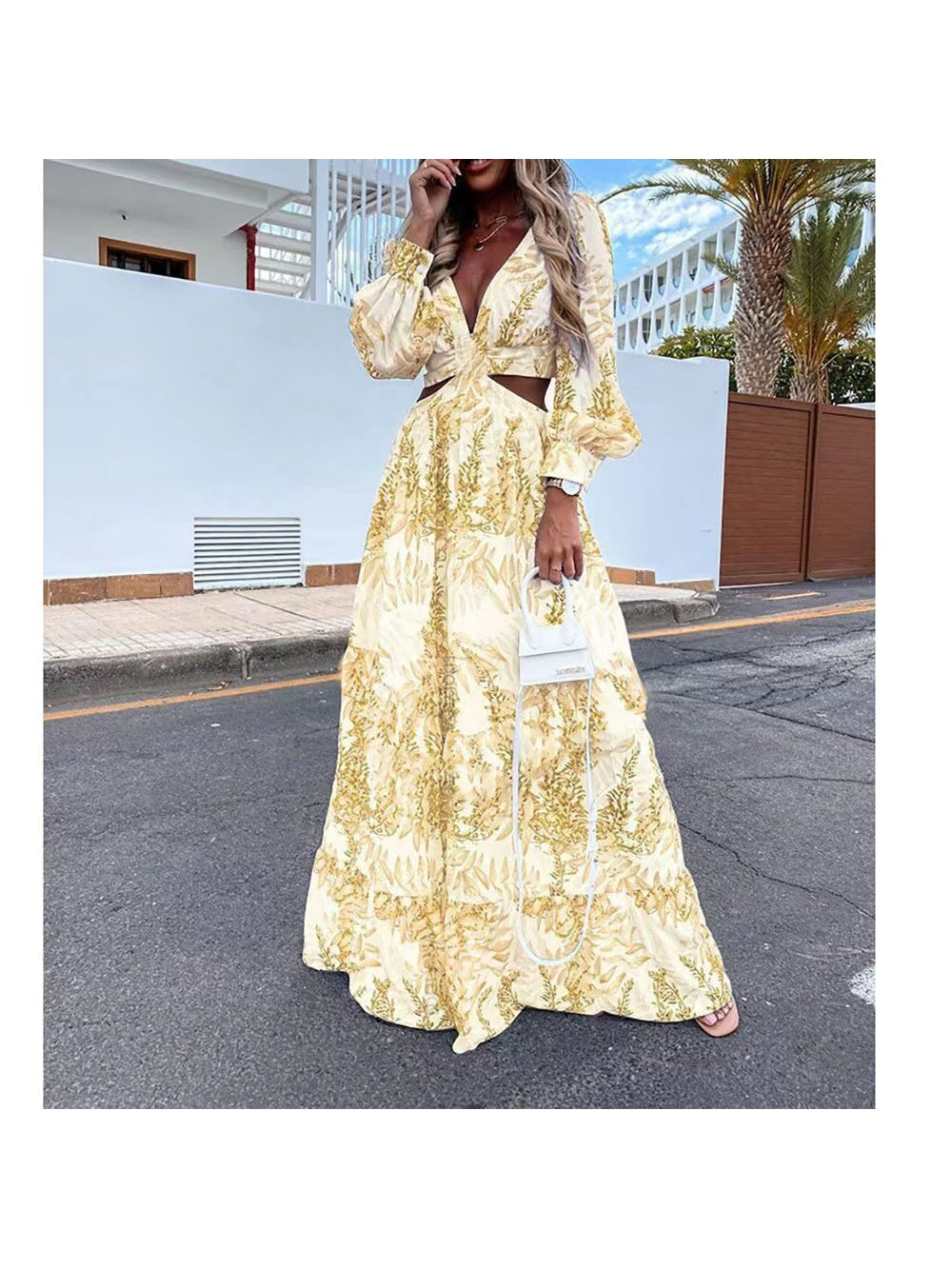 Woman wearing a pale yellow floral cutout maxi dress with long puff sleeves and waist cutouts, holding a white handbag.