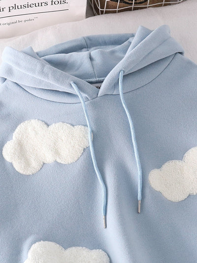 Light blue hoodie with white fluffy cloud patches on the chest and sleeves, drawstring hood with metal tips, soft fleece fabric.
