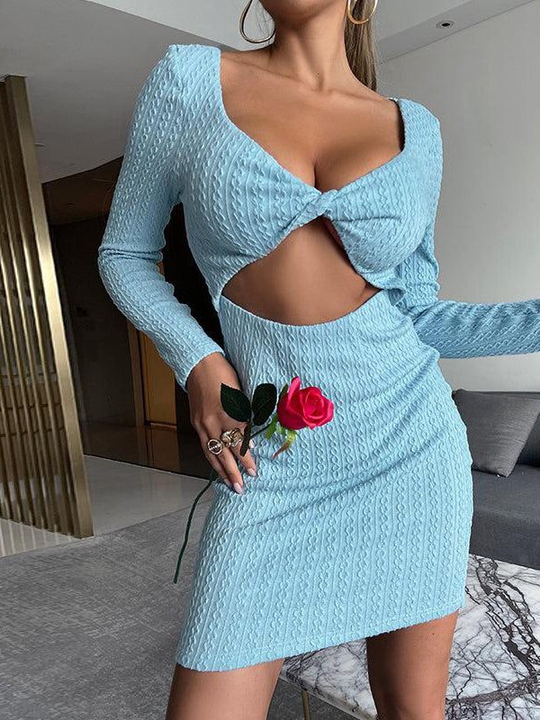 Light blue knit bodycon mini dress with twisted front knot and midriff cutout, long sleeves, model holding a pink rose.