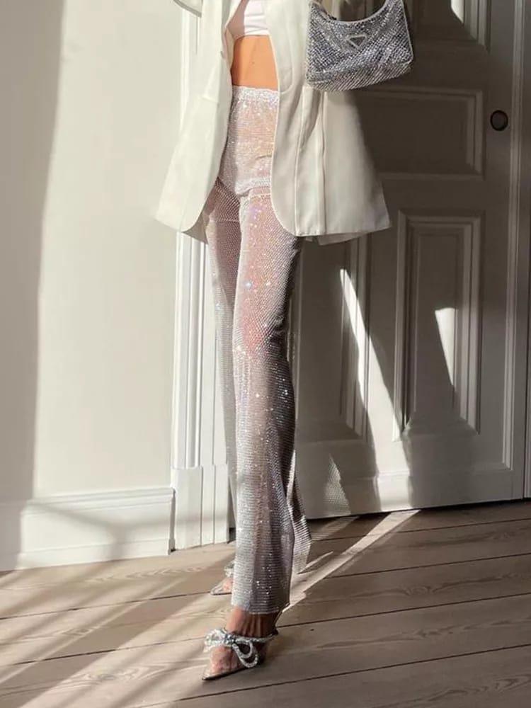 Silver sequin rhinestone pants with a white blazer; sparkling silver bag draped over the shoulder; rhinestone sandals.