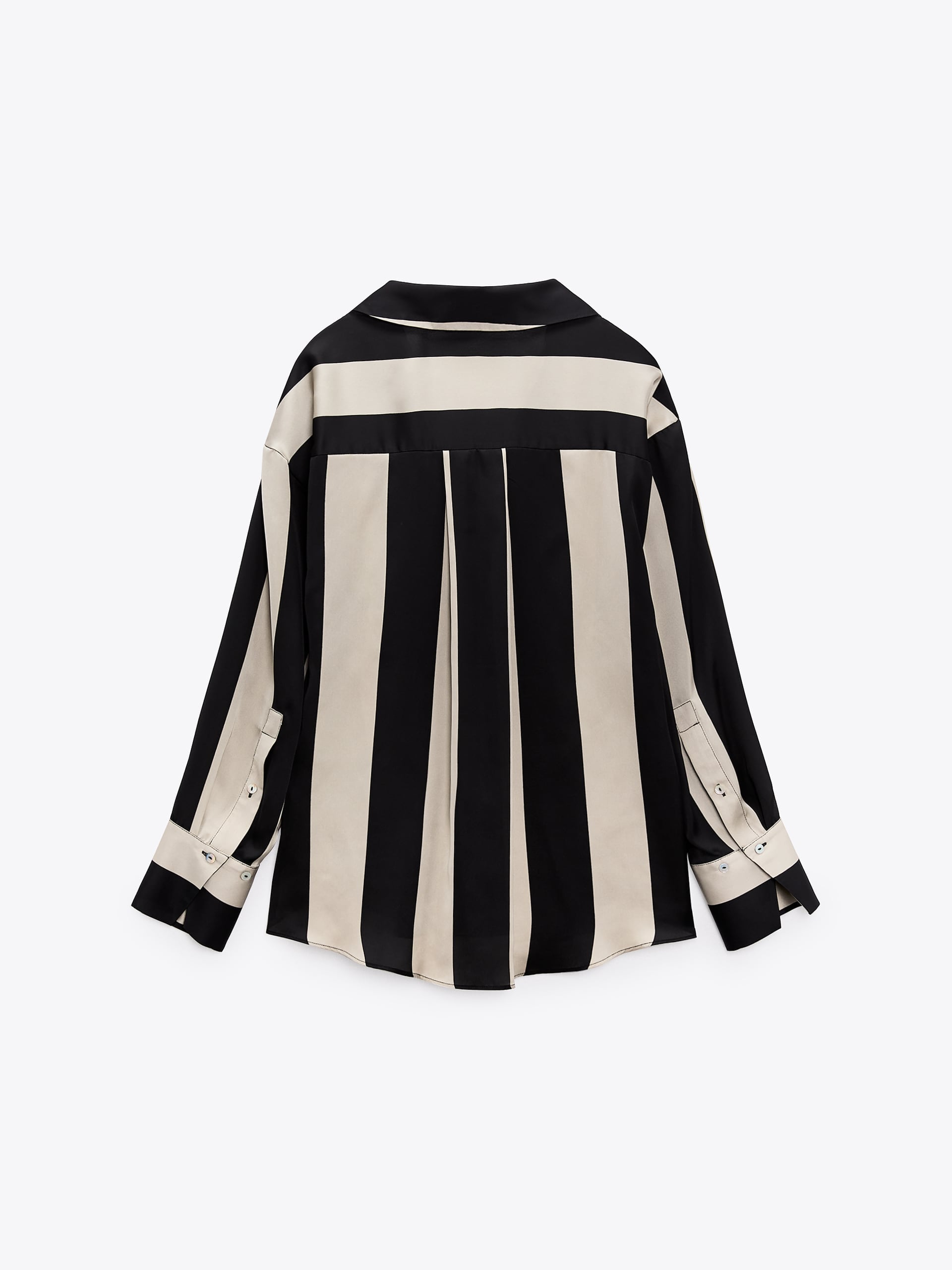Back view of an oversized satin shirt with cream and black vertical stripes, drop shoulders, pleated back panel, and long buttoned cuffs.