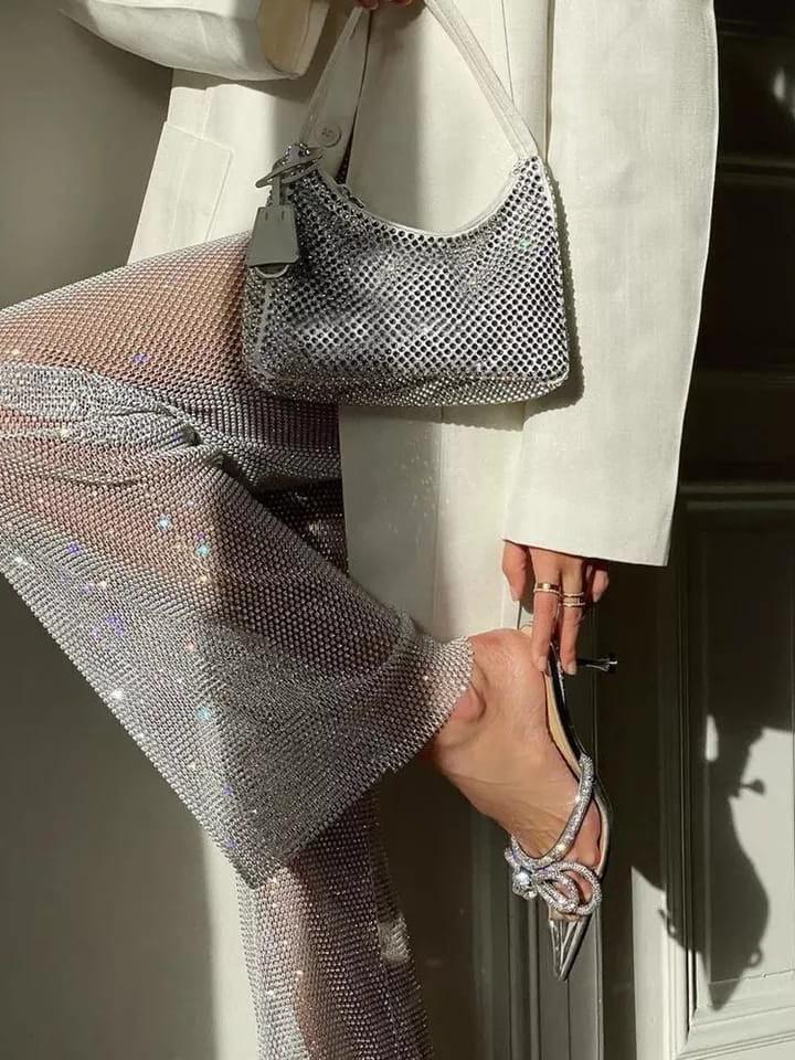 Silver rhinestone-studded pants with a small crystal handbag and glittery strappy sandals.