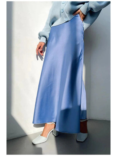 Pastel blue satin A-line floor-length skirt, paired with a light blue knit cardigan and white mules.