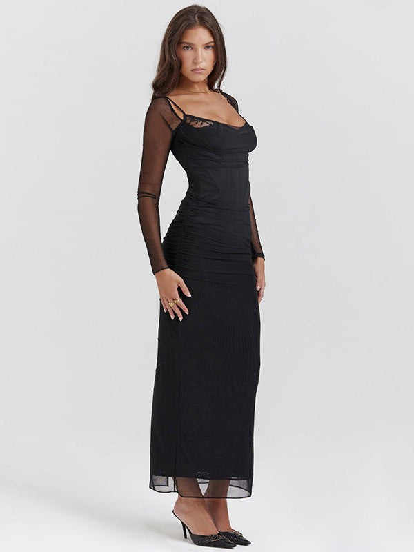 Model in black maxi with thin spaghetti straps, sheer mesh long sleeves, and a ruched bodice; long dress with sheer hem.