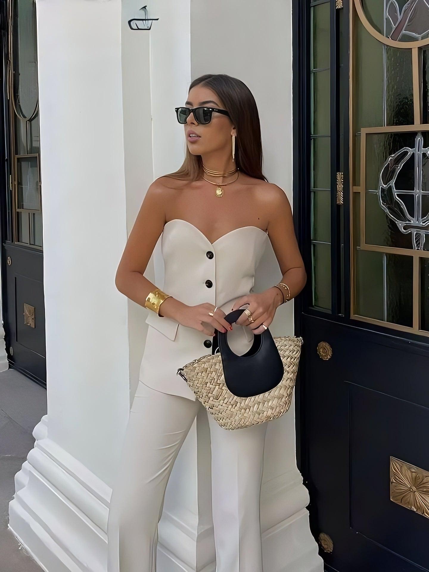 Ivory strapless corset top with front buttons and matching wide-leg pants; model with sunglasses and woven straw bag.