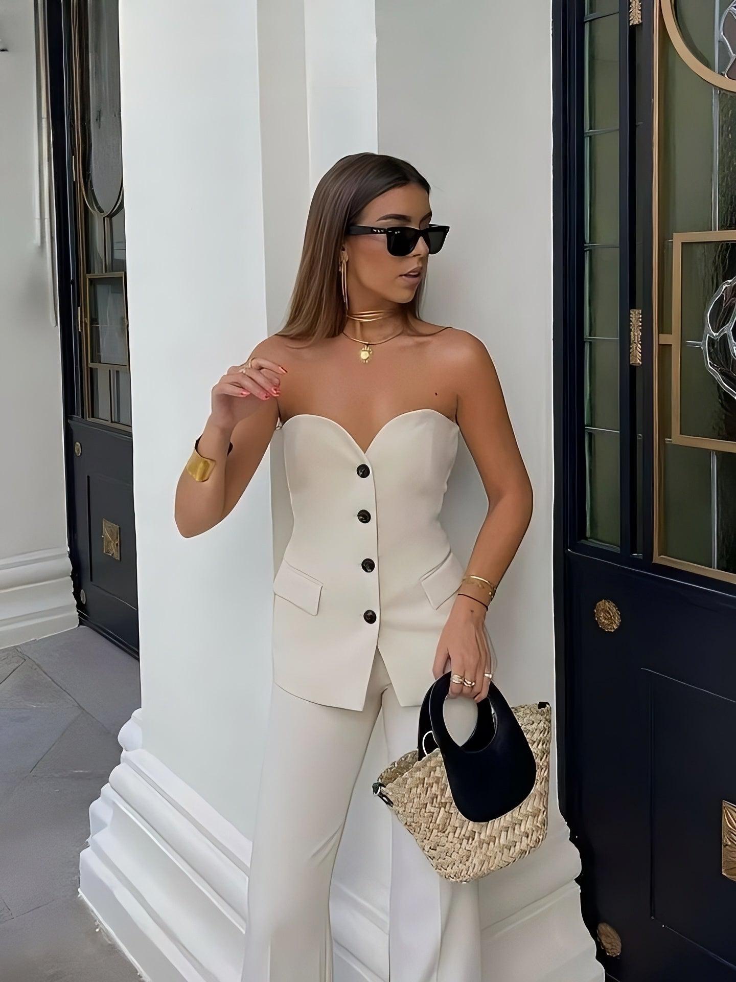 Cream strapless corset top with front buttons and matching wide-leg pants; woman in sunglasses holding straw bag.
