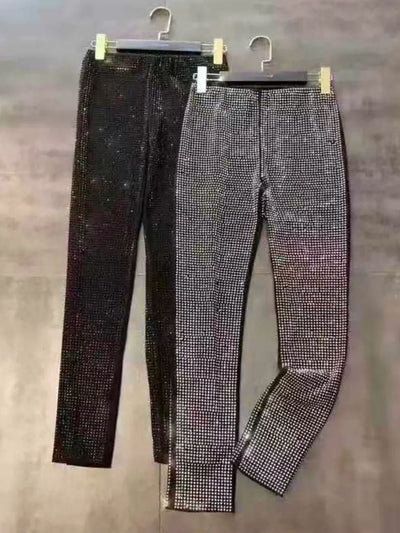 Two rhinestone pants on hangers, one black and one silver, fully encrusted with rhinestones.