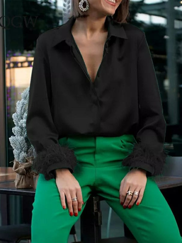 Black satin blouse with feathered fur cuffs paired with green high-waisted pants; model with red nails and bold earrings.