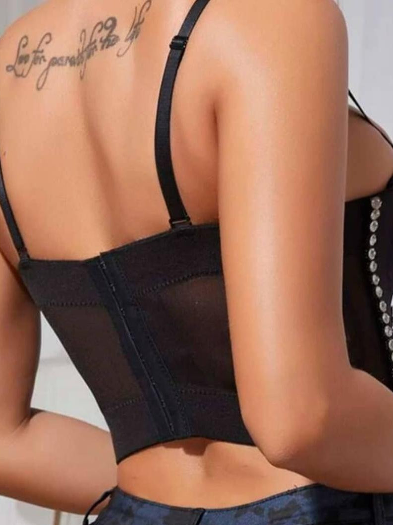 Back view of black bustier-style bralette with boning and adjustable straps; tattoo on upper back visible.