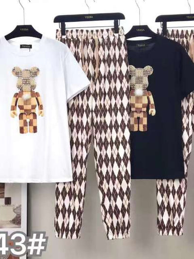 White and black T-shirts with a blocky bear graphic, paired with brown-and-cream argyle pants on a clothing rack.